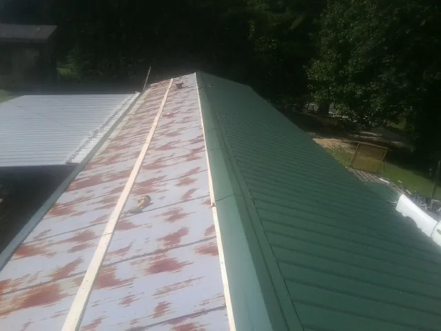 Old rusted panels beside newly installed green metal roofing — Wind Damage Roof Repair by Roofing Brothers in Seaton