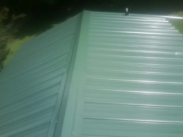 New green metal panels meeting at the ridge of a roof — Flat Roof Repair work by our crew in Seaton