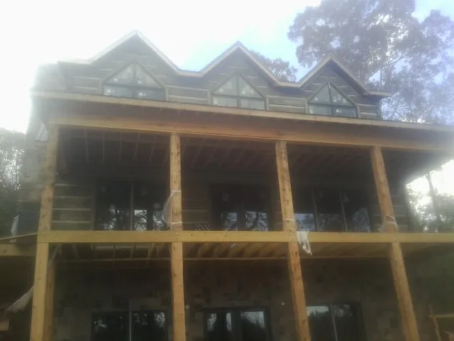 Dormers and porch framing on a large log home under construction — Roof Coating work by our crew in Seaton