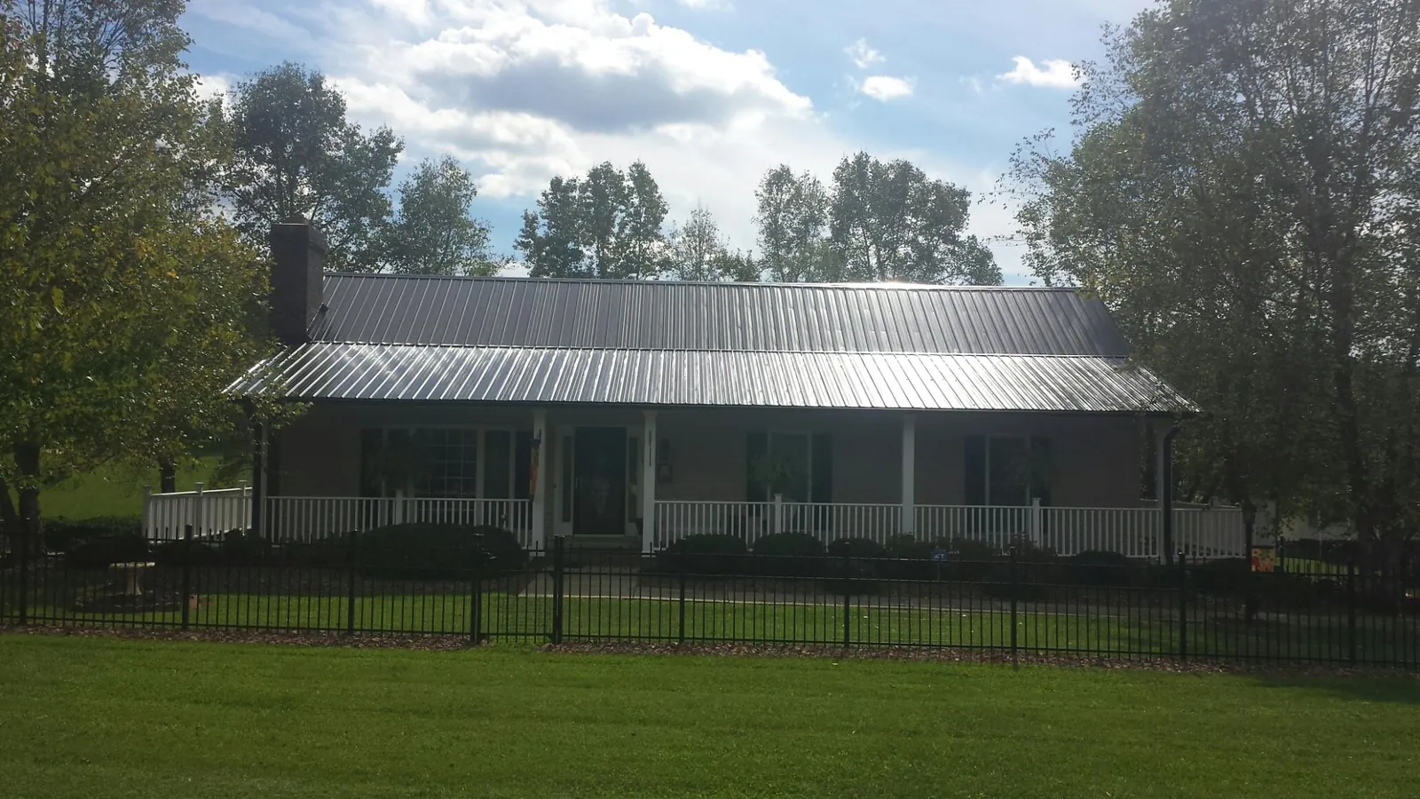 Gray metal roof on a brick ranch with a full width front porch — Gutter Guard Installation work by our crew in Seaton