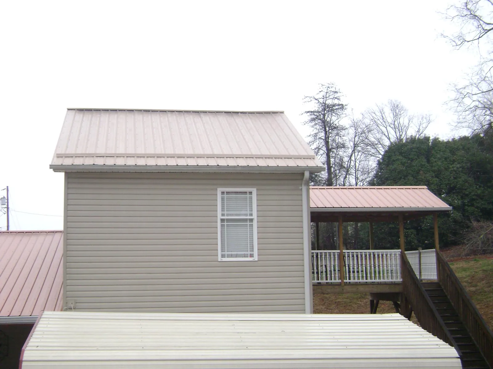 Tan metal roofs on a two story addition and attached porch, from a Roof Replacement job in Seaton