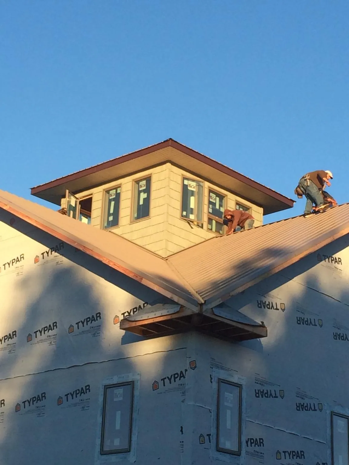 Roofers working around a rooftop cupola on a new metal roof at sunset — Roof Waterproofing in Seaton by Roofing Brothers